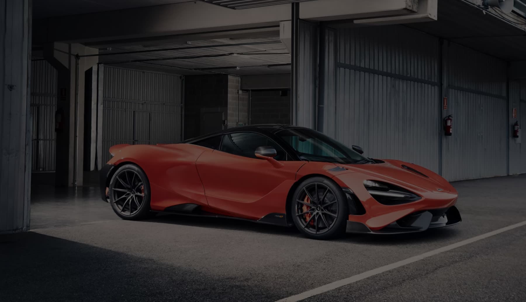 Papaya orange supercar in a dark pit garage
